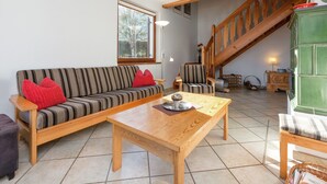 A living room with a sofa, armchairs, a wooden coffee table, and a staircase. - Quaint Holiday in Gröbming near Skiing (Groebming)
