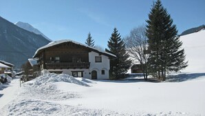 Un bâtiment enneigé, doté d’une façade en bois, d’un balcon et surplombant un paysage montagneux.