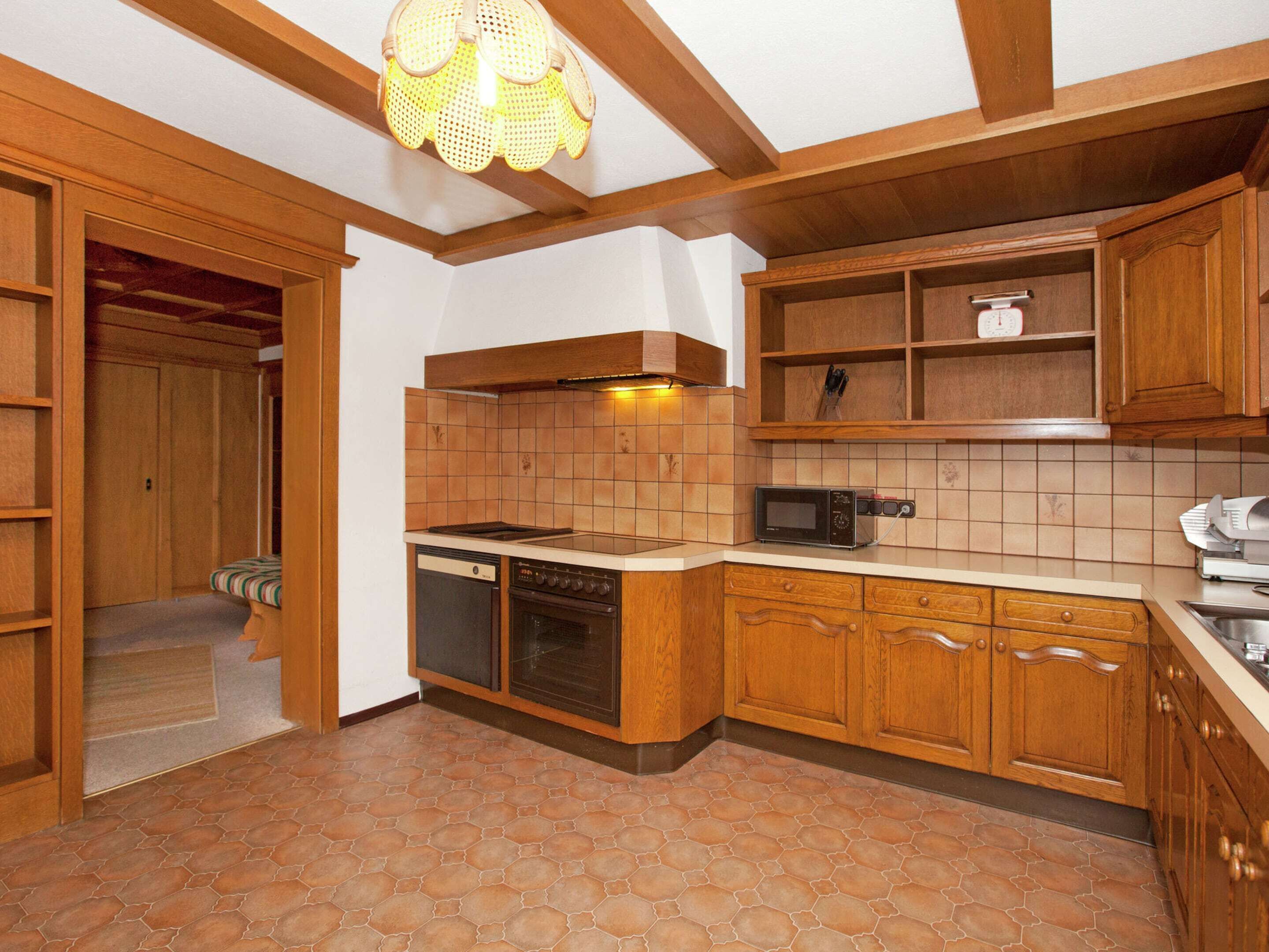 A kitchen with wooden cabinets, a microwave, a dishwasher, and a stove.