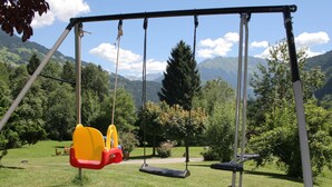 A swing set in a park with a mountainous backdrop.