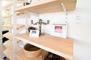 A wooden shelf with a candelabra, a framed artwork, and a digital clock.