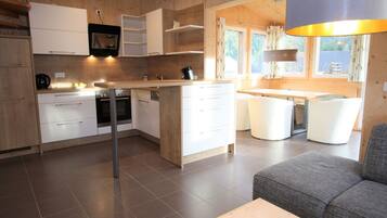 Una cocina moderna con armarios blancos, una isla central y un comedor con mesa y sillas.