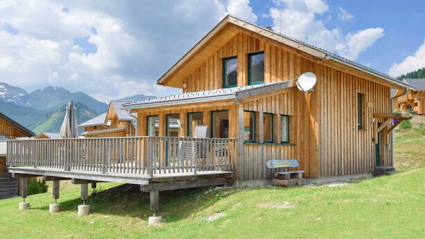 A wooden chalet with a balcony, large windows, and a view of mountains. - Wooden Chalet in Hohentauern With Sauna (Hohentauern)