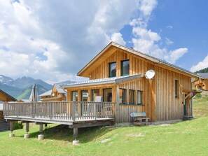 A wooden chalet with a balcony, large windows, and a view of mountains. - Wooden Chalet in Hohentauern With Sauna (Hohentauern)