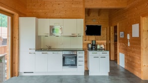 Moderni keittiö, jossa on valkoiset kaapit, sisäänrakennettu uuni, mikroaaltouuni ja kahvinkeitin.
