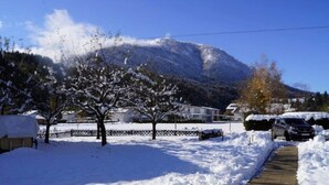 A snow-covered pathway leading to a building with a mountain in the background.
