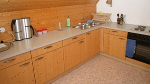A kitchen with wooden cabinets, a granite countertop, a coffee maker, a sink, and a stove. - Scenic Holiday Home in Deutsch Griffen near Hochrindl (Deutsch-Griffen)