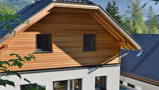 A two-story wooden house with a sloped roof, large windows, and a view of mountains. - Chalet Only 200 m From ski Lift With Sauna (Bad Kleinkirchheim)