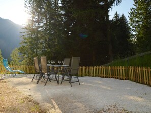 A table set outdoors with chairs, surrounded by a gravel area and a wooden fence.