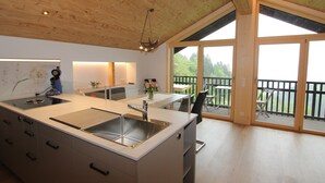 A modern kitchen with a central island, large windows, and a deck area. - Cozy Apartment in Schruns Vorarlberg near Ski Area Montafon (Schruns)