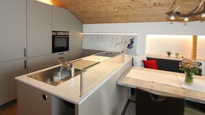 A modern kitchen with a central island, stainless steel appliances, and a wooden ceiling. - Cozy Apartment in Schruns Vorarlberg near Ski Area Montafon (Schruns)