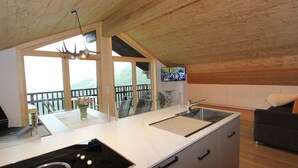 A modern kitchen with a large island, a built-in stove, and a sink. There is a balcony with a view of the mountains. - Cozy Apartment in Schruns Vorarlberg near Ski Area Montafon (Schruns)