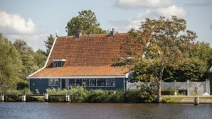 A house with a red-tiled roof, a dock, and a body of water in the foreground. - B&B Saenliefde (Wormer)