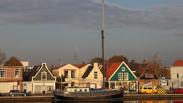 A waterfront scene with a boat docked near buildings with distinct architectural styles, including a green house with a red roof.