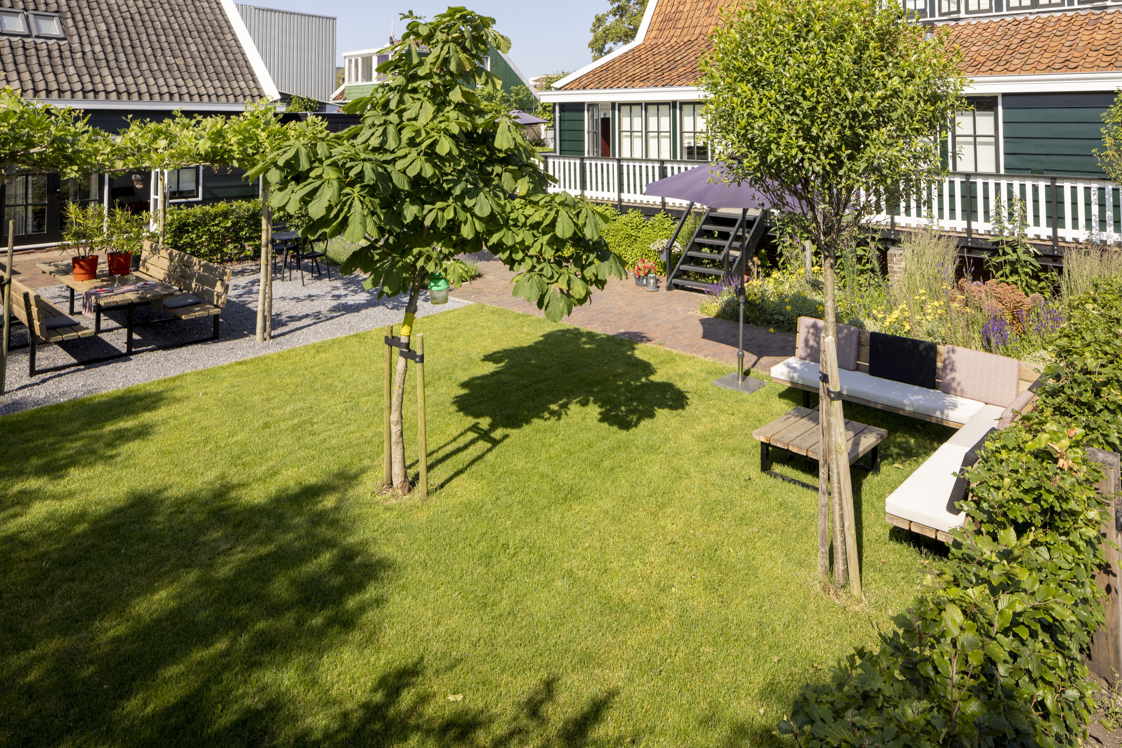 Ein gepflegter Garten mit einer hölzernen Bank, einem kleinen Tisch und verschiedenen Pflanzen.