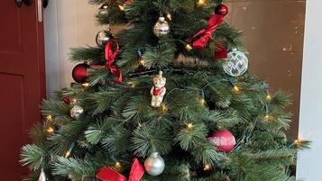 A Christmas tree with red and silver ornaments and lights, placed in a wicker basket.