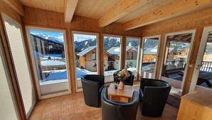 A wooden interior with large windows, a tiled floor, and a table with chairs. - Comfortable Chalet in Hohentauern with Whirlpool near City Center (Hohentauern)
