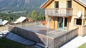 A wooden chalet with a balcony, surrounded by mountains. - Comfortable Chalet in Hohentauern with Whirlpool near City Center (Hohentauern)