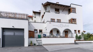 Ein zweistöckiges Gebäude mit Garage, einem Balkon mit Sitzgelegenheit im Freien und einem Schild mit der Aufschrift 'HAUS Elisabeth'.