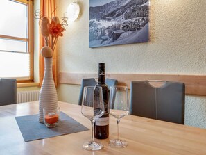 A dining table with a bottle of wine, two glasses, and a decorative vase with dried flowers. - Vibrant Apartment near Ski Area in Fiss (Fiss)