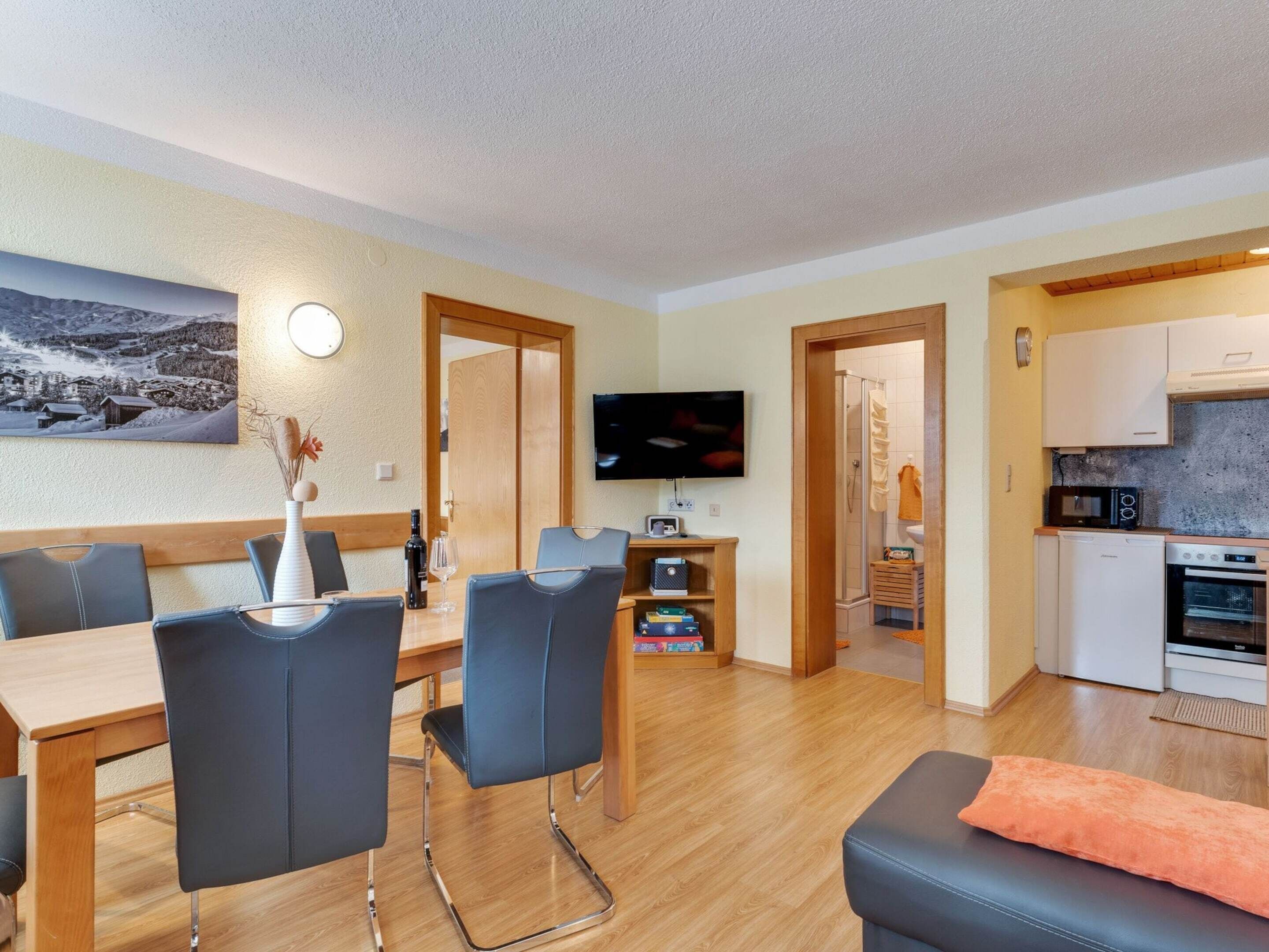 Una sala de estar moderna con comedor, televisor y kitchenette.