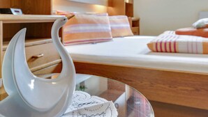 Ein Hotelzimmer mit Bett, Holz-Kopfstütze, Nachttischen und einer dekorativen weißen Schwan.