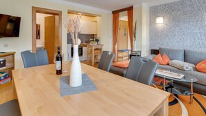 Ein modernes Wohnzimmer mit einem Holzesstisch, grau gepolsterten Stühlen und einer Wand mit grauem Muster.