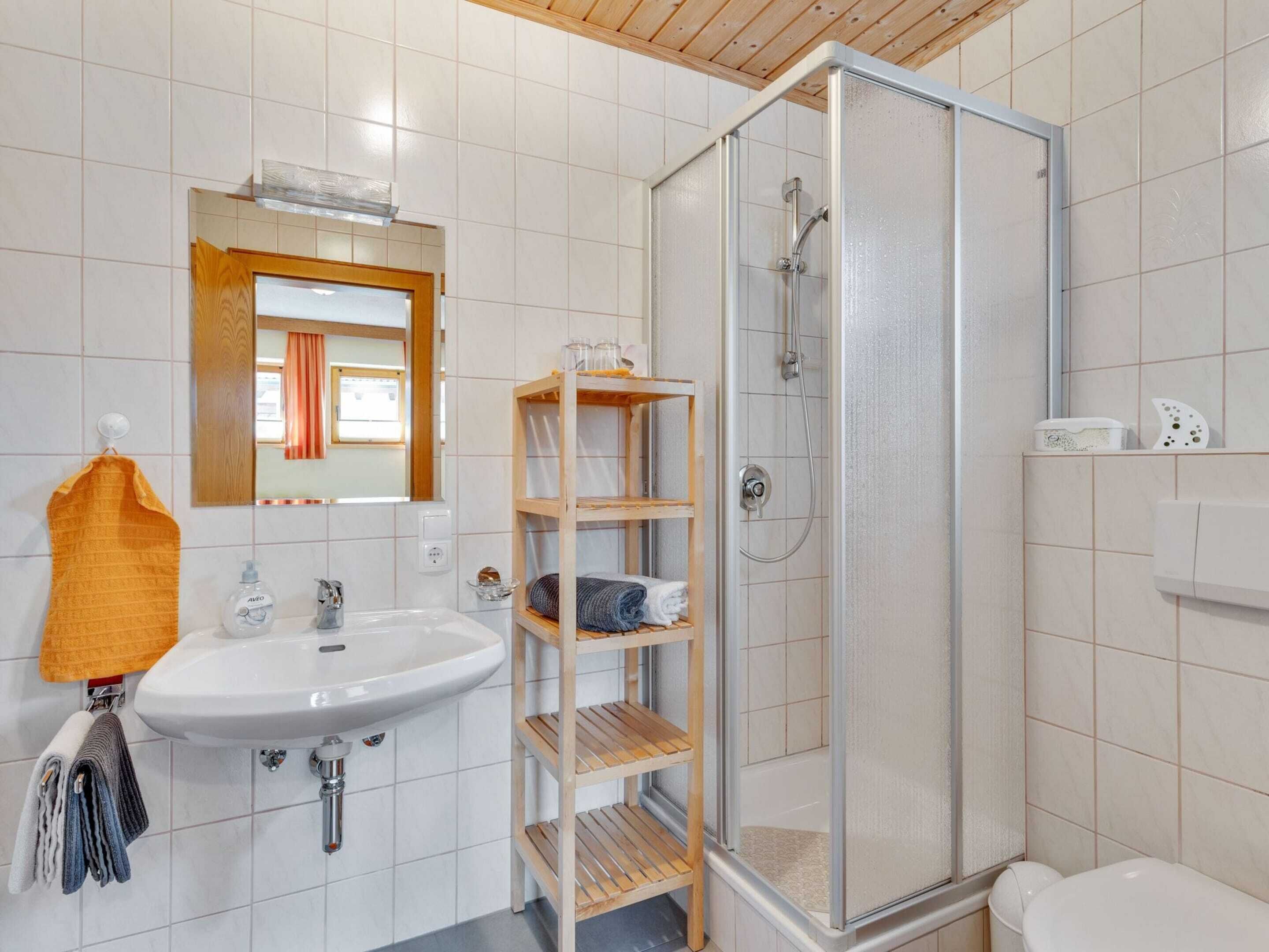 A bathroom with a white sink, a mirror, a shower enclosure, and a toilet.