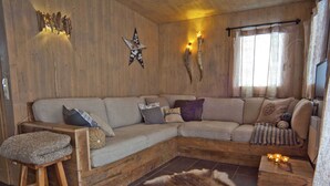 Ein gemütliches Blockhaushaus-Interieur mit einem Holzsofa, einem Fellteppich und einer Holzbank.