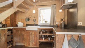 Eine rustikale Küche mit Holzausstattung, einem eingebauten Ofen und einem Fenster mit Vorhang.