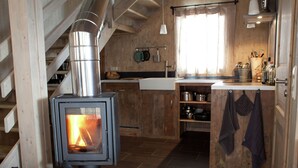 Eine rustikale Küche mit Holzofen, Holzschränken und einem Fliesenboden aus Stein.