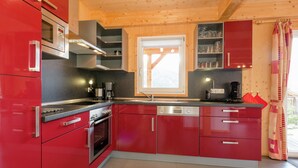 Eine moderne Küche mit roten Schränken, Edelstahlgeräten und einem Fenster, das für natürliches Licht sorgt.