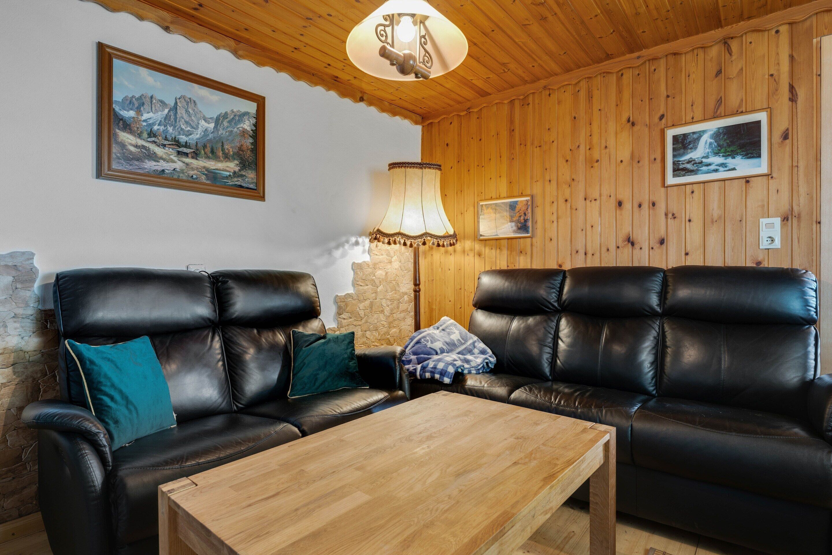 Una sala de estar acogedora con dos sofás de cuero, una mesa de centro de madera y una pared de piedra.
