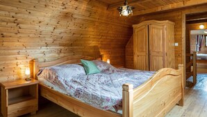 Camera da letto in una baita di legno con un letto, comodini e un armadio.