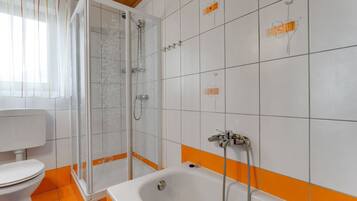 A bathroom with a shower, toilet, and bathtub.