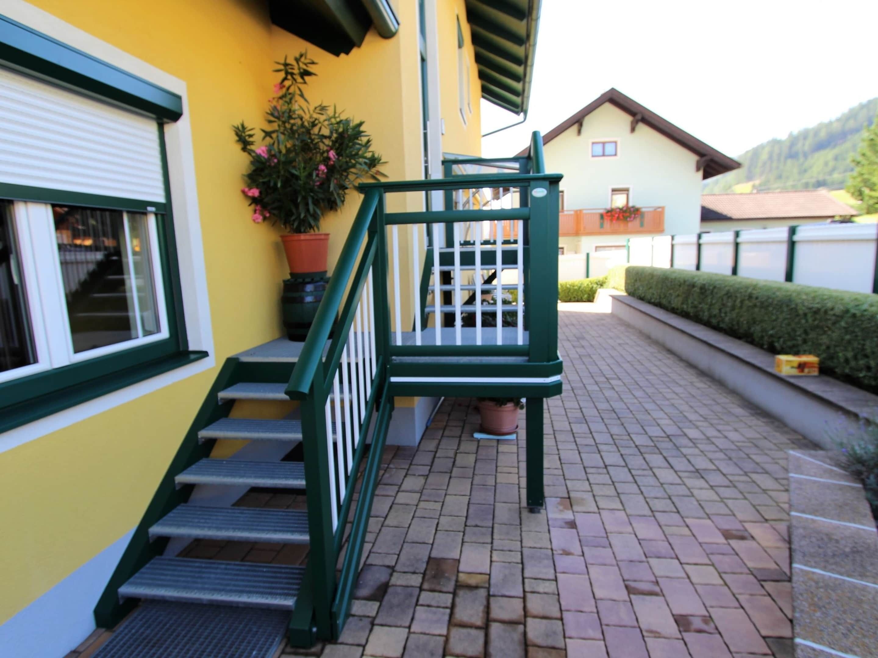 A staircase with green railings leading to a building entrance.