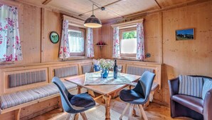 A wooden cabin interior with a dining table, two chairs, a bench, and a sofa. - Holiday Home in Tyrol Near Ski Slopes (Matrei in Osttirol)