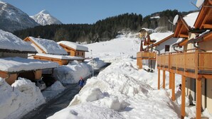 Un village de montagne enneigé, avec des bâtiments en bois et un ciel dégagé.