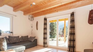 Un salon comprenant un canapé, une table basse en bois et une vue sur un espace extérieur, accessible par une porte vitrée.