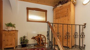Una escalera de madera con barandilla de metal, un radiador y una ventana en lo alto.