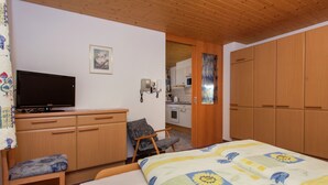 Un dormitorio con una cama, un escritorio con televisor, una silla y un armario.