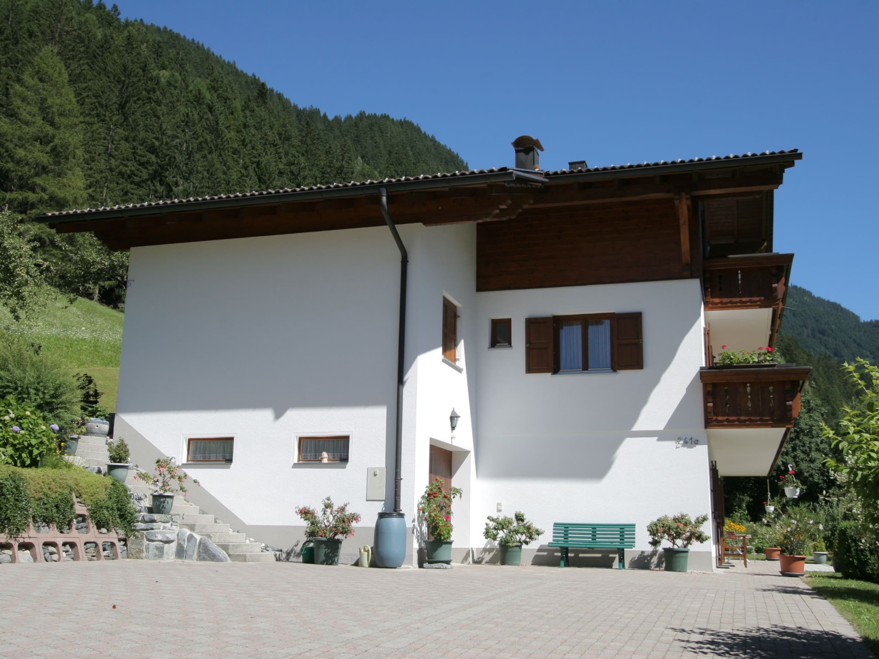 Un bâtiment à deux étages, doté d’une façade blanche, de balcons en bois et d’un toit recouvert de tuiles.
