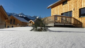 A wooden chalet with a balcony, surrounded by snow-covered ground and mountains in the background. - Wooden Chalet in Hohentauern With Sauna (Hohentauern)