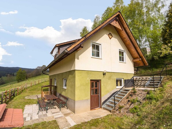 A two-story house with a sloped roof, a wooden staircase, and a patio with outdoor furniture. - Chalet in Sankt Andra Near Koralpe Ski Area (Sankt Andra)