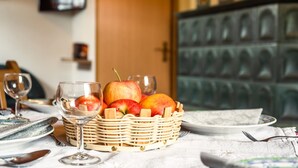 A dining table with a fruit basket, wine glasses, and cutlery. - Chalet in Sankt Andra Near Koralpe Ski Area (Sankt Andra)
