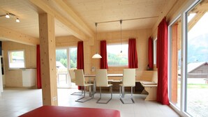 A wooden interior with a dining area, red curtains, and large windows. - Nice Chalet in Hohentauern / Styria With Sauna (Hohentauern)