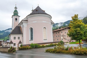 A pink church with a bell tower and a dome, surrounded by greenery and a mountain backdrop. - Modern Apartment in Brixen im Thale Near Ski Area (Brixen im Thale)