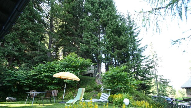 A garden with a lawn, a yellow umbrella, and two lounge chairs. - Queitly Located Chalet near Resort Center of Nassfeld (Hermagor-Pressegger See)