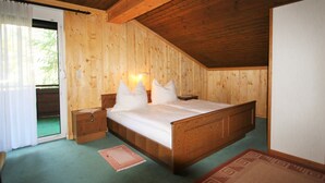 A wooden-paneled bedroom with a bed, bedside tables, and a window with curtains. - Queitly Located Chalet near Resort Center of Nassfeld (Hermagor-Pressegger See)