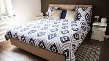 Een slaapkamer met een bed, nachtkastjes, een raam en een vloerkleed.
